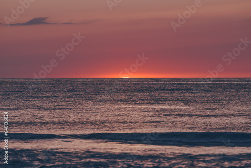 The glowing sun sinking on the horizon of the sea or ocean