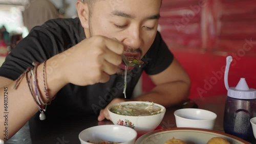 Man Eating Soto Mie a spicy Indonesian noodle soup Bihun dish commonly found in Indonesia, Malaysia, and Singapore photo
