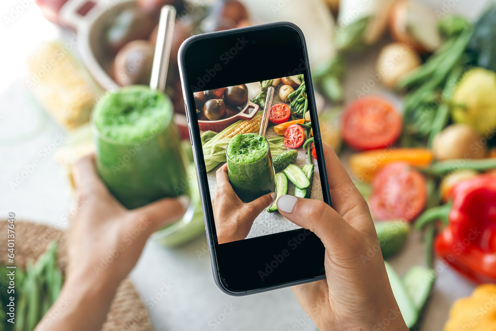 Woman taking a photo of a smoothie on her smartphone, close up. Woman taking a photo of a smoothie on her smartphone, close up.