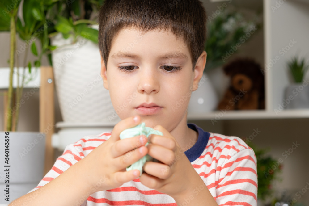 A six-year-old boy plays with slime while sitting at a table at home. A toy for the development of fine motor skills and creativity in children A six-year-old boy plays with slime while sitting at a table at home. A toy for the development of fine motor skills and creativity in children