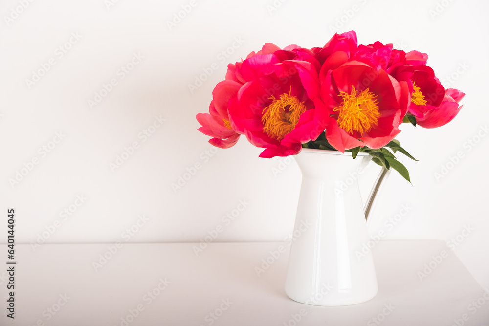 Beautiful bouquet of fresh coral red peony flowers in full bloom in vase against white background. Copy space for text. Mother's day, Birthday card.