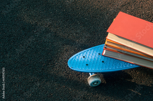 Blue skateboard with books outdoor shot back to school concept learning sunny picture
