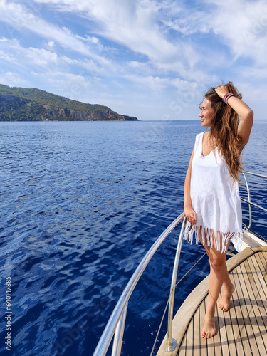 beautiful girl on the deck of a boat while traveling on the sea with a view of the mountains © Nataliya