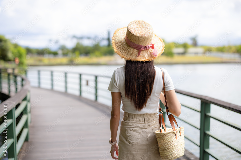 Woman walk along the wooden path beside the river