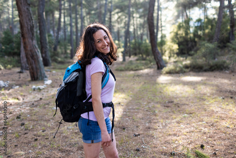 smiling girl walks through the forest with a backpack smiling girl walks through the forest with a backpack