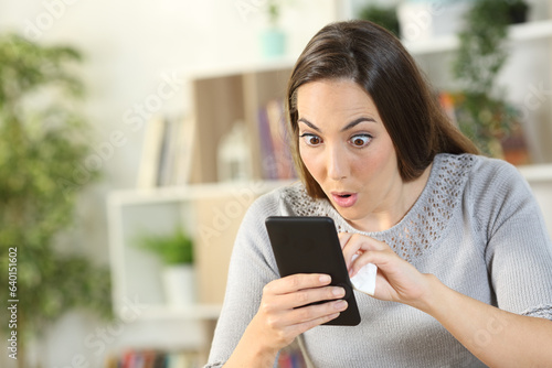 Картината върху платно Surprised woman cleaning smart phone at home