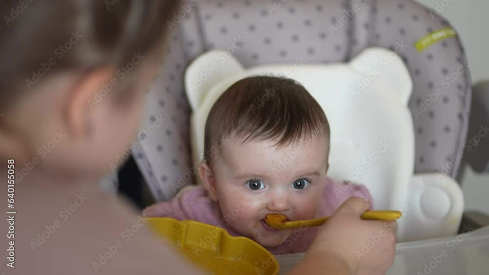 baby newborn eats. happy family dream weaning concept. dirty mess baby girl eating vegetables. baby daughter eats on a feeding chair indoors dirty face. naughty dirty babe indulges while feeding . baby newborn eats. happy family dream weaning concept. dirty mess baby girl eating vegetables. baby daughter eats on a feeding chair indoors dirty face. naughty dirty babe indulges while feeding .