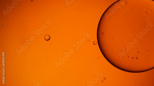 Gold artistic of oil drop floating on the water. Pastel color bubble for background. Orange background of oil drop.