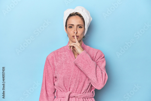 Woman in pink robe after shower keeping a secret or asking for silence.