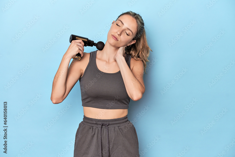Athlete using neck massager in blue studio Athlete using neck massager in blue studio