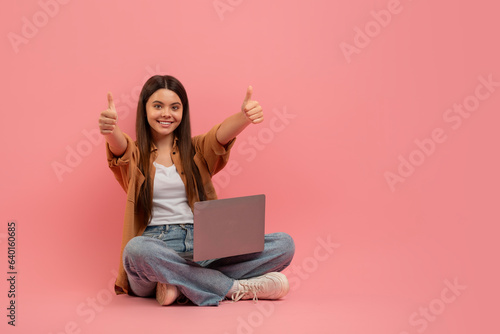 Portrait Of Happy Teen Girl With Laptop On Laps Showing Thumb Up © Prostock-studio