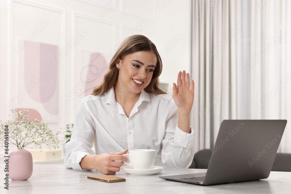 Happy woman with cup of drink using laptop at white table Happy woman with cup of drink using laptop at white table