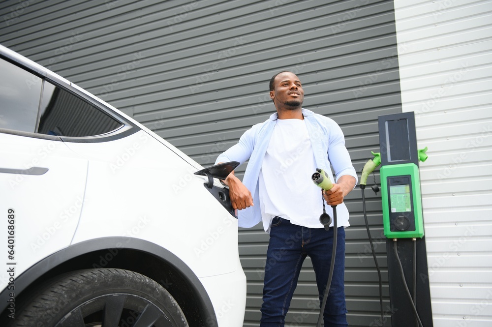 Man Plugging In Electric Car Outside Office In Car Park Charging