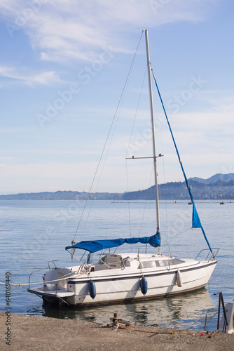 Sailboat with furled sails moored to the pier, against the background of the sea bay