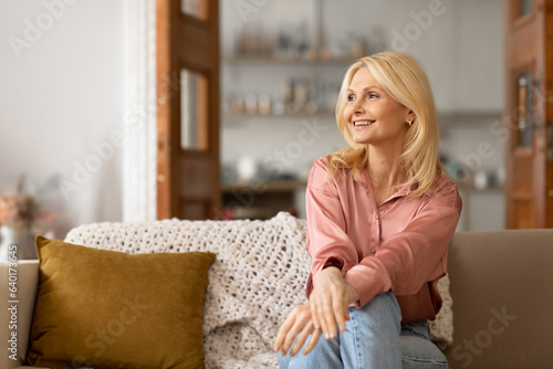 Smiling Mature Blonde Lady Posing On Couch Looking Aside Indoor