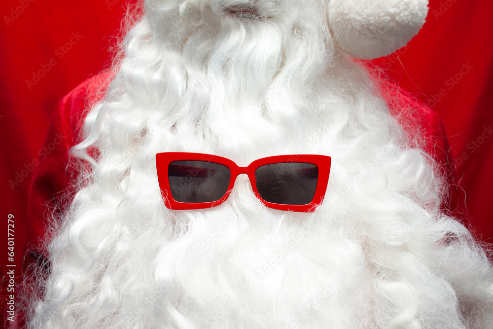 red sunglasses lie on the white long beard of santa claus for christmas, new year's accessory and decoration red sunglasses lie on the white long beard of santa claus for christmas, new year's accessory and decoration