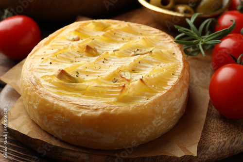 Tasty baked brie cheese with rosemary and cherry tomatoes on wooden board, closeup