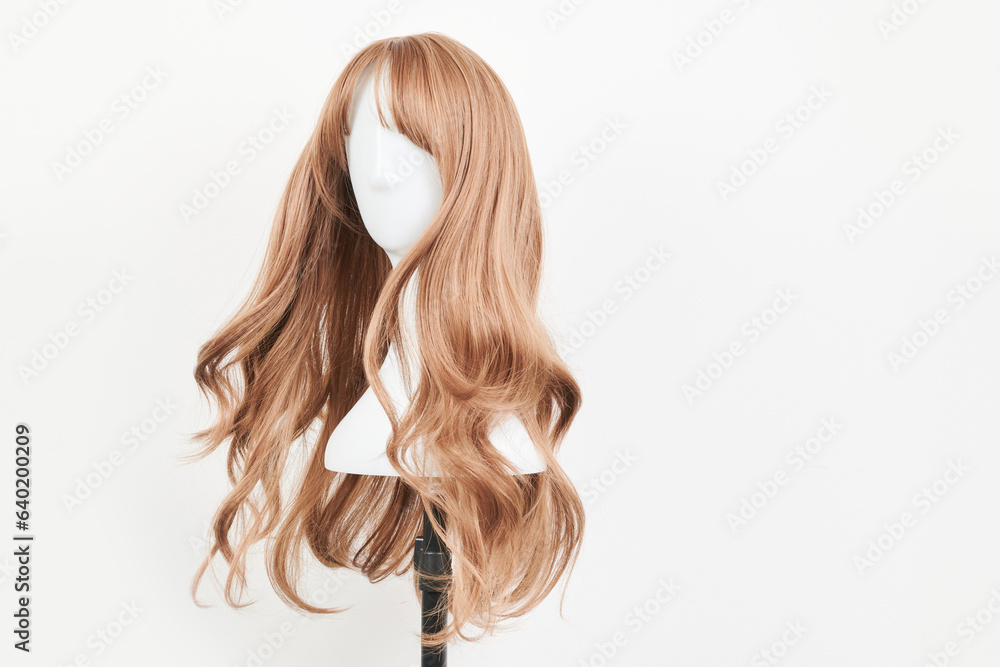 Natural looking dark blonde wig on white mannequin head. Long fair hair cut on the plastic wig holder isolated on white background Natural looking dark blonde wig on white mannequin head. Long fair hair cut on the plastic wig holder isolated on white background
