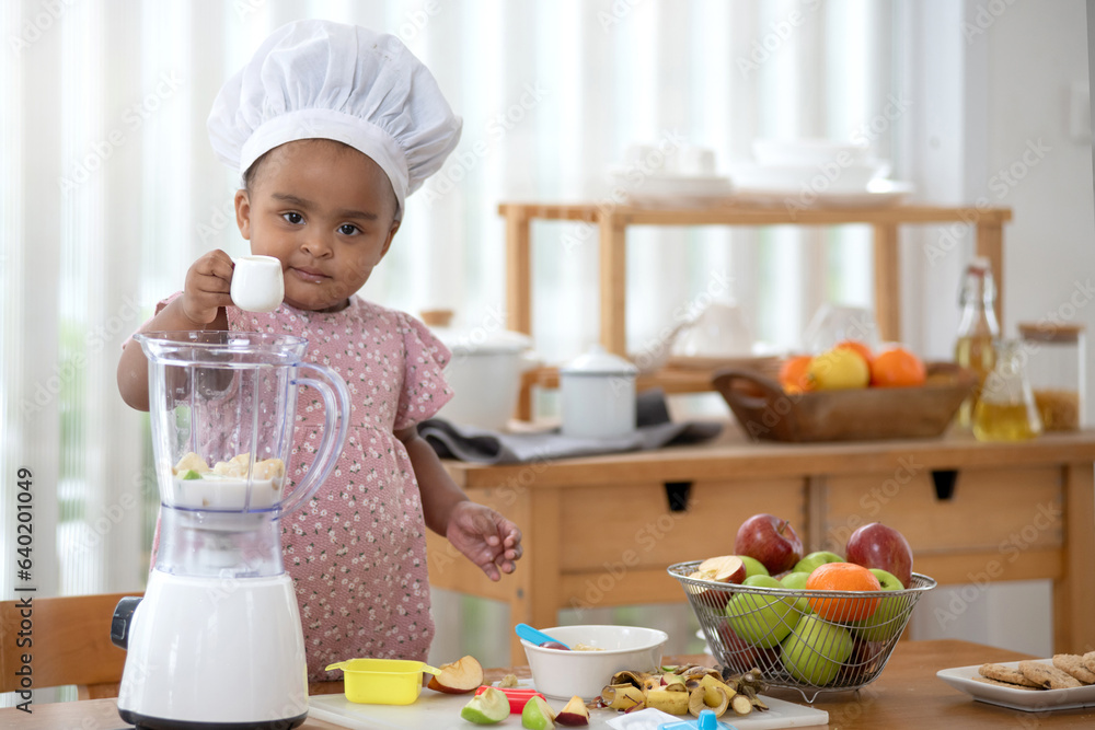 Cute African baby girl prepare to make smoothies at home, put the milk and fruit into the mix, homemade drink at home Cute African baby girl prepare to make smoothies at home, put the milk and fruit into the mix, homemade drink at home