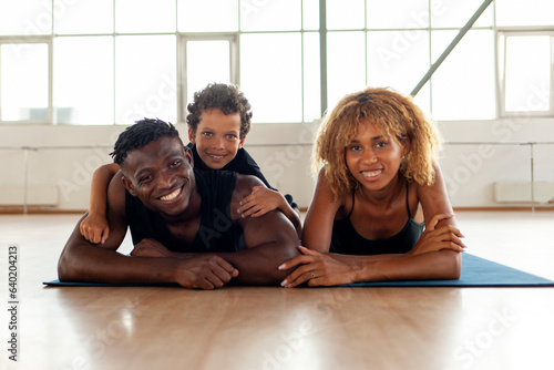 happy african american young family lies and rests on yoga mat in the gym, mom dad and son go in for sports together