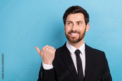 Photo of cool thoughtful agent guy dressed black suit looking showing thumb empty space isolated blue color background