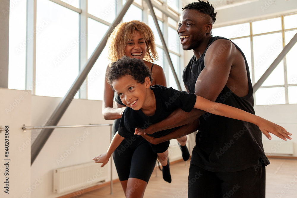 athletic african american family in sportswear holding and carrying son in the air and playing in gym athletic african american family in sportswear holding and carrying son in the air and playing in gym