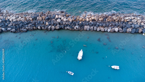 Barca ormeggiata nel porto vista dall'alto, fotografia con drone mostra la massicciata della marina, acqua del mare limpido ed una barca all'ormeggio photo