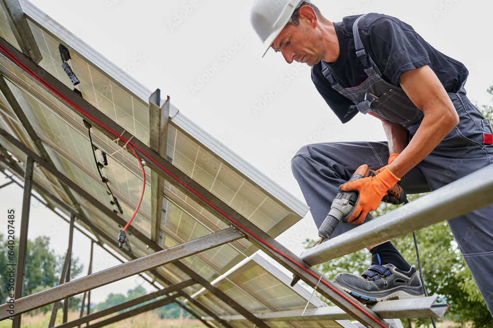Worker fixing metal beams with electric drill for solar panels. Concept of renewable and ecological energy. Modern technology and innovation. Worker fixing metal beams with electric drill for solar panels. Concept of renewable and ecological energy. Modern technology and innovation.