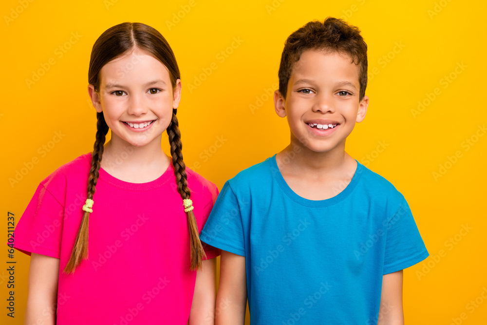 Photo of sweet cheerful preteen schoolchildren wear t-shirts smiling isolated yellow color background Photo of sweet cheerful preteen schoolchildren wear t-shirts smiling isolated yellow color background