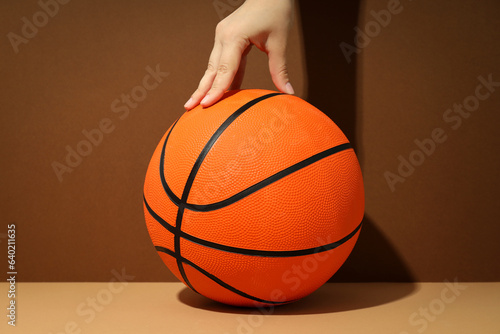 Female hand and basketball ball on two tone background © Atlas