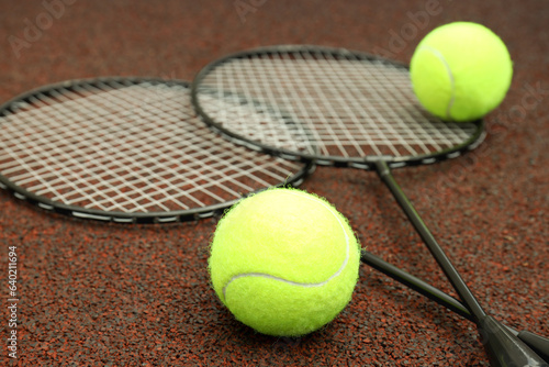 Badminton rackets and tennis balls on playground rubber coating