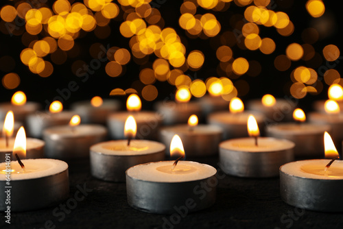 Burning small candles on black background, close up