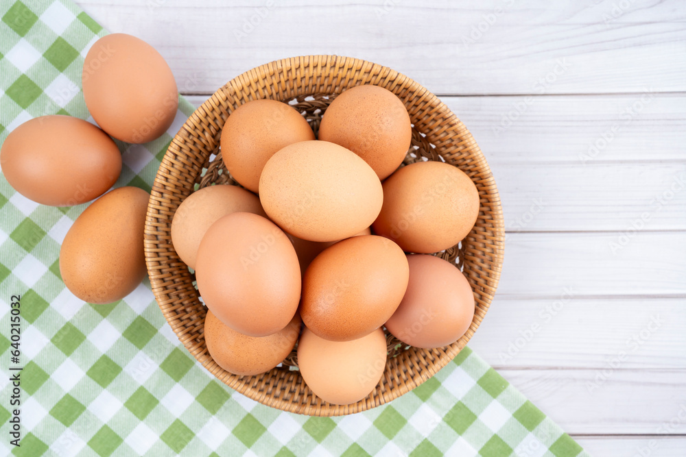 The Fresh eggs in a wooden weave basket and tablecloth on wooden background. The Fresh eggs in a wooden weave basket and tablecloth on wooden background.