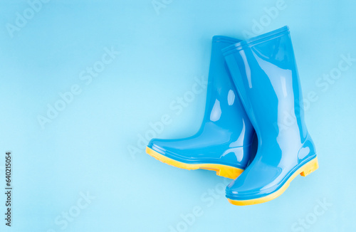 Pair of blue rubber boots on light blue background, top view with empty space for your text. photo