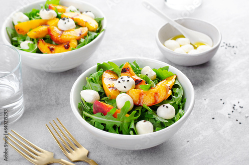 Grilled Peach Salad with Arugula and Mozzarella on Bright Concrete Background