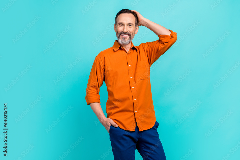 Photo of satisfied businessman wear orange shirt blue pants hand head model posing successful boss isolated on cyan color background Photo of satisfied businessman wear orange shirt blue pants hand head model posing successful boss isolated on cyan color background