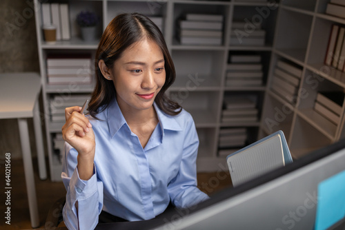 Asian woman sitting in the office working overtime in the middle of the night, employee working overtime to get work done on time. The concept of overtime and hard work of company employees.