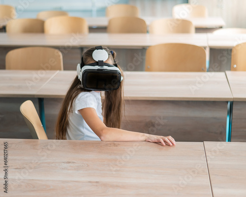 Caucasian schoolgirl wearing virtual reality glasses in the classroom.