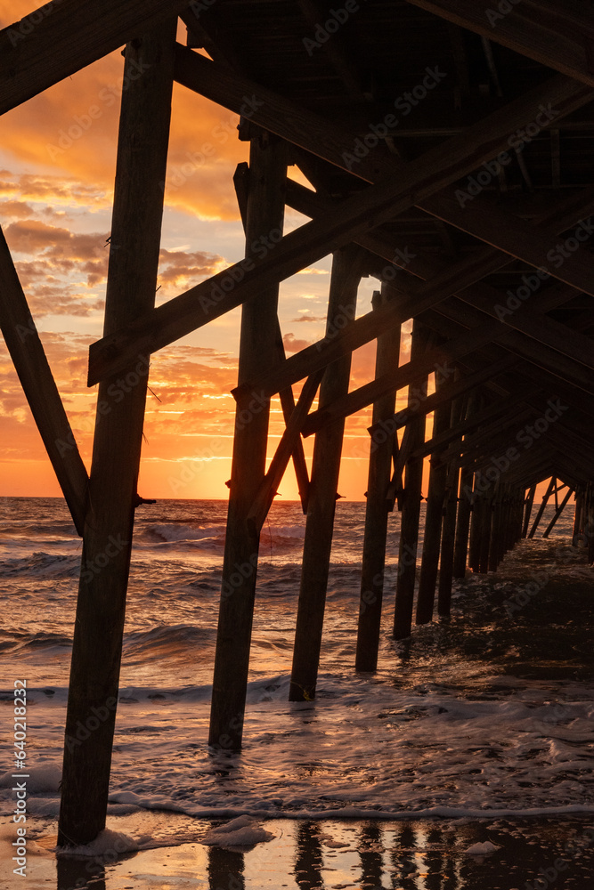 Sunrise through the pilings of the Pawley's Island fishing Pier one week after half the pier was destroyed by Hurricane Ian