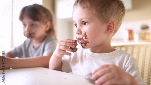 children eat chocolate. dirty little baby kids in the kitchen eating chocolate in the morning. happy family eating sweets kid lifestyle dream concept. baby dirty face eating chocolate cocoa