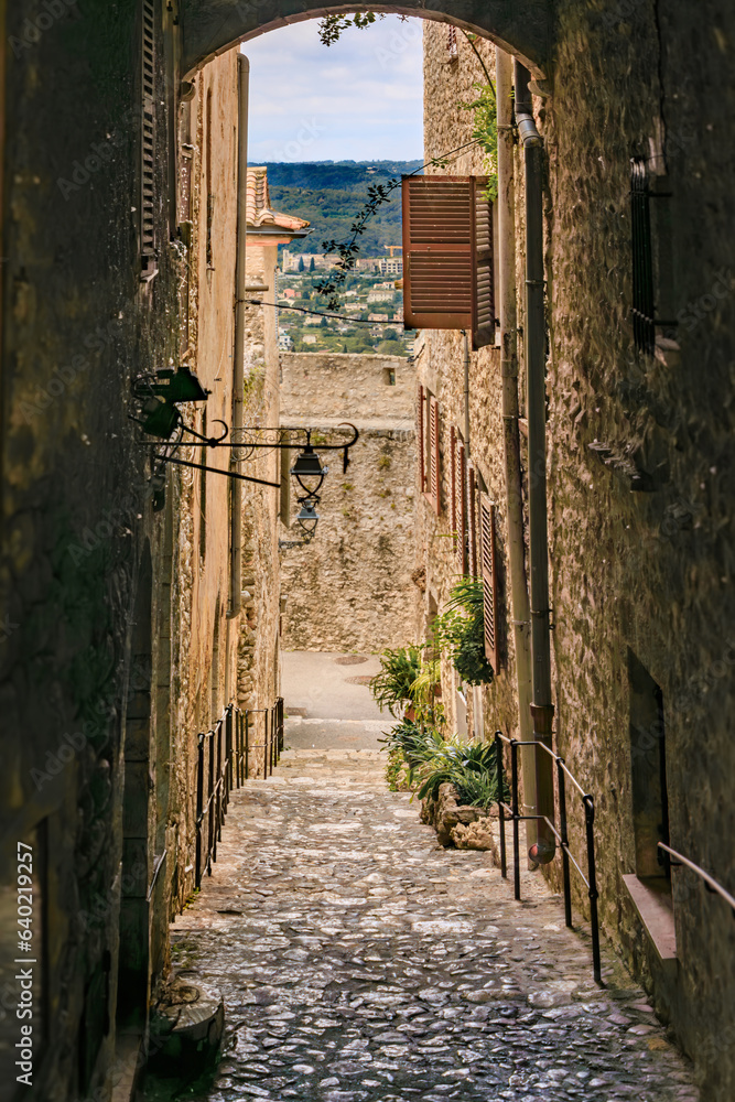 Narrow arched passage between traditional old stone houses on a street in the medieval town of Saint Paul de Vence, French Riviera, South of France