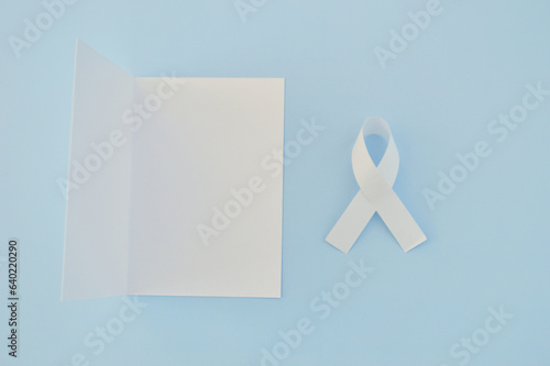 White ribbon as a symbol of peace and white paper on a blue background. World Day of Peace. Day Of Human Fraternity. International Day of Living Together in Peace. International Human Solidarity Day