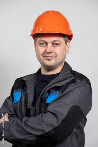 A young man construction worker in a safety helmet and work uniform on a white background