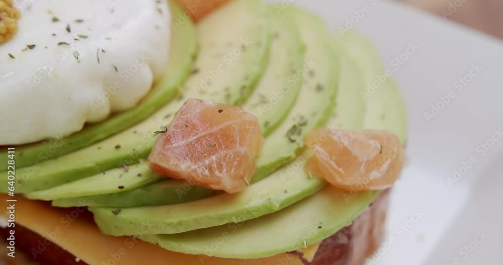 Delicious croissant with cheese, avocado, mustard, salmon filet and egg benedict. Close up. Tasty and healthy breakfast. Fast food. Burger with poached egg. Concept of healthy eating. Delicious croissant with cheese, avocado, mustard, salmon filet and egg benedict. Close up. Tasty and healthy breakfast. Fast food. Burger with poached egg. Concept of healthy eating.
