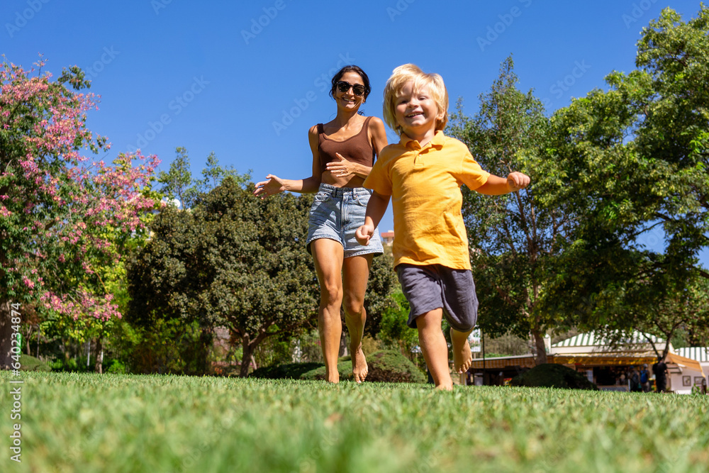 Fototapeta premium mother and little son run in the park on the green grass