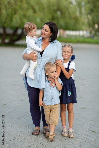 Mom with a todler son and two small children in the park, Mother's Day concept