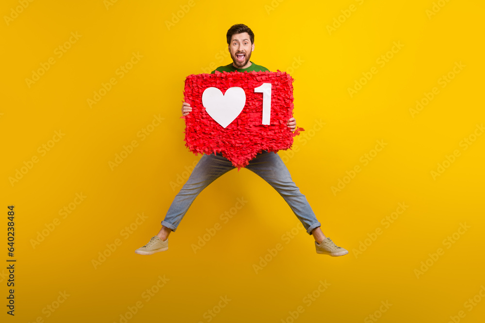Full body photo of jumper influencer popular vlogger holding pinata like symbol subscribe his channel isolated on yellow color background - obrazy, fototapety, plakaty 