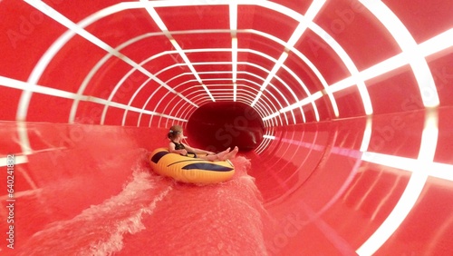 Young Girl Riding Swim Tube Water Slide in Water Park