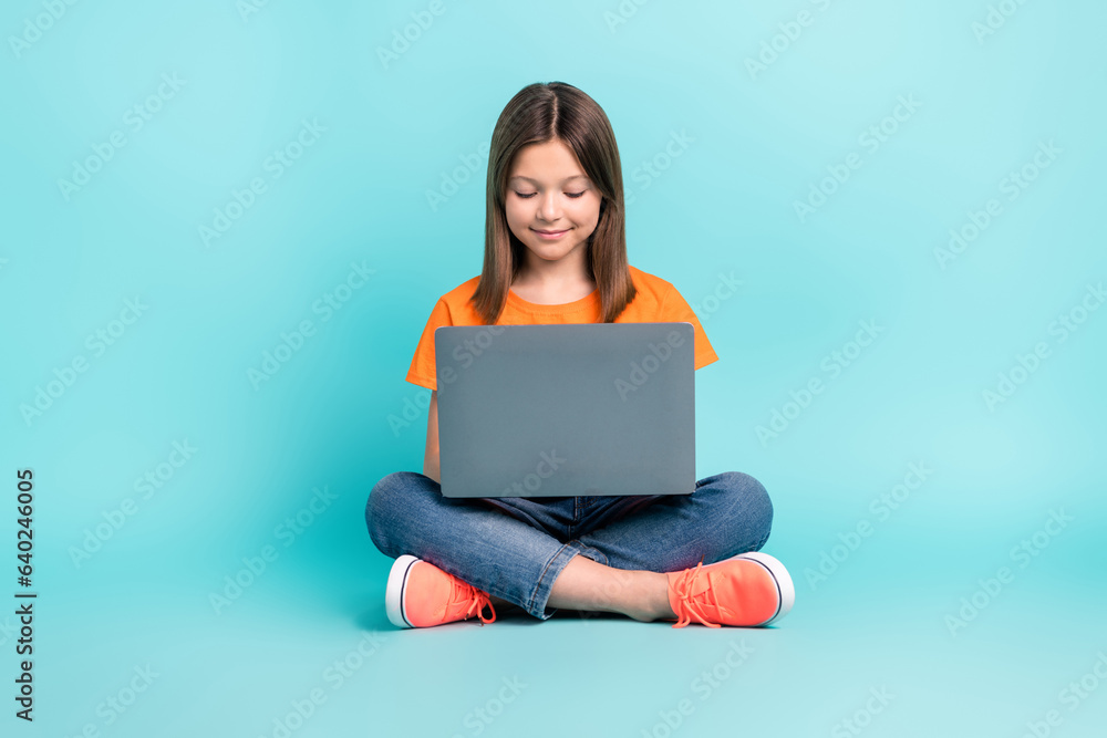 Photo of charming funny girl wear stylish clothes sitting floor typing texting sms isolated on cyan color background Photo of charming funny girl wear stylish clothes sitting floor typing texting sms isolated on cyan color background