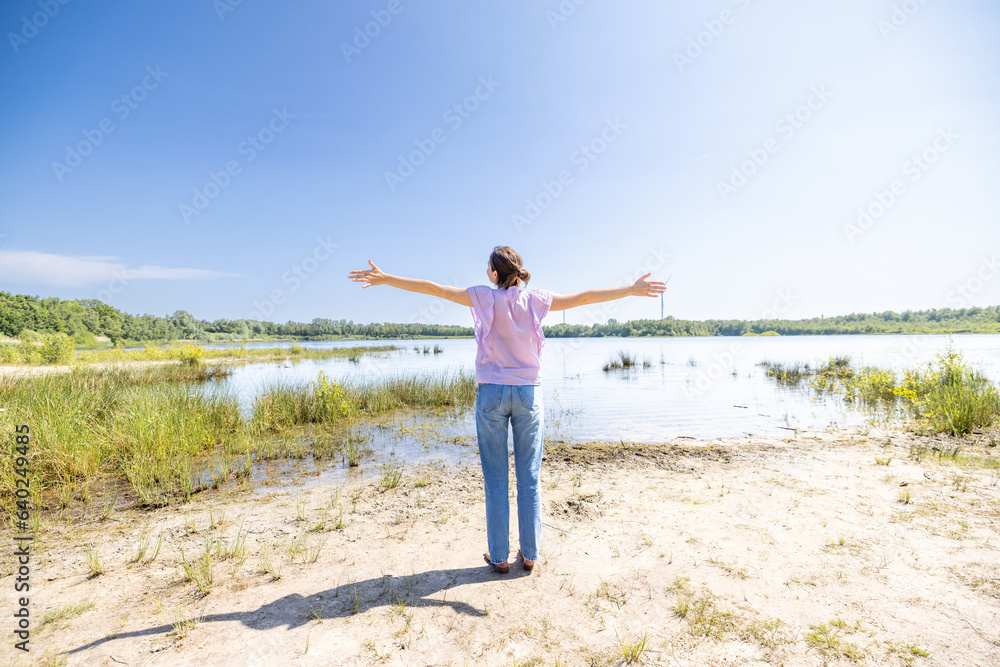 Experience the exuberance of victory and joy in this vibrant image. A happy woman raises her arms in a victory gesture, smiling with the backdrop of lush green trees and nature's beauty. Amidst the Experience the exuberance of victory and joy in this vibrant image. A happy woman raises her arms in a victory gesture, smiling with the backdrop of lush green trees and nature's beauty. Amidst the